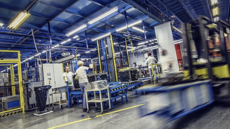 factory workers inside warehouse surrounded by machinery