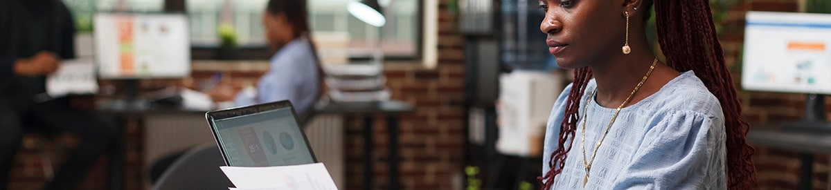 Kobieta siedzi przy biurku w biurze i przegląda dokumenty